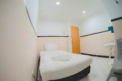a small room with a white bed and a sink at XX Mitr Inn - Phuket Old Town in Phuket Town
