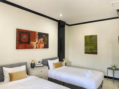 two beds in a room with paintings on the wall at Wink City 4th Patong in Patong Beach