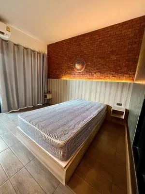 a large bed in a room with a brick wall at Bang Tao cozy studio in Ban Thalat Choeng Thale