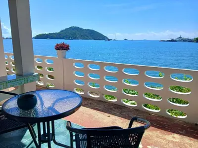 a table and chairs on a balcony overlooking the water at Water's Edge Resort , in Panwa Beach