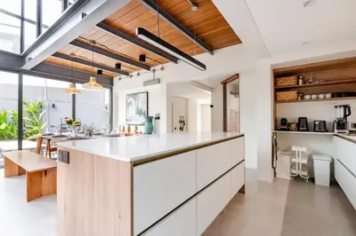 an open kitchen with white cabinets and a large island at Stylish Mansion for Leisure with Garden & Pool in Laguna Phuket
