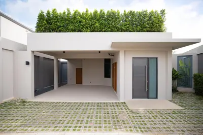 a white house with a green hedge at Stylish Mansion for Leisure with Garden & Pool in Laguna Phuket