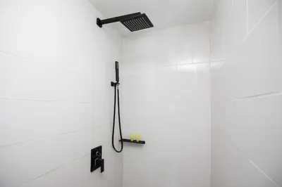 a shower in a bathroom with a white wall at Poolside Duplex In Nai harn UTL A102 in Rawai Beach