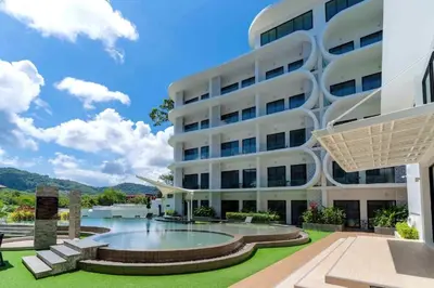 a large white building with a swimming pool in front of it at Poolside Duplex In Nai harn UTL A102 in Rawai Beach