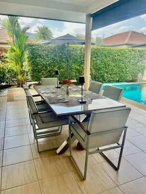 a dining table with chairs and an umbrella on a patio at Stunning 2-Bedroom Pool Villa in Ban Thalat Choeng Thale