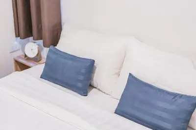 a white bed with two blue pillows on it at 24sqm room close to beach and Muay Thai gym in Ao Nang Beach