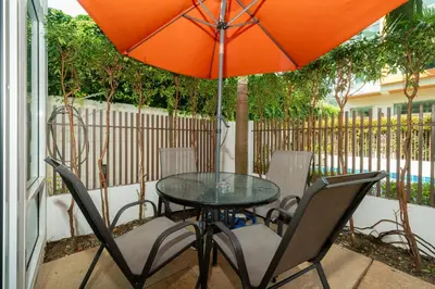 a table and chairs with an orange umbrella on a patio at AP Nest Villas Residence - Tropical Pool Access, near Kamala Beach in Kamala Beach