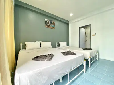 two twin beds in a room with a mirror at Mini Thai Guesthouse Patong in Patong Beach