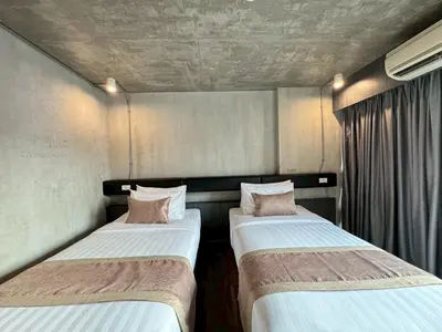 two beds in a small room with curtains at Aspira Central Patong in Patong Beach