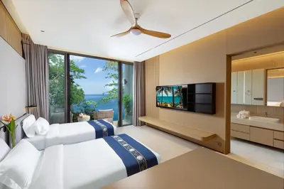 a bedroom with two beds and a large window at The Aquila Villa in Kamala Beach