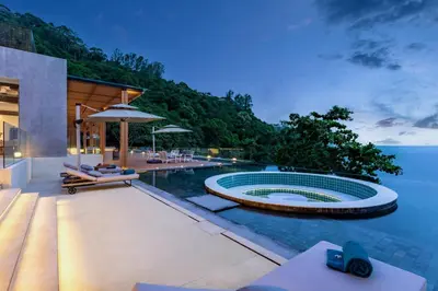 a swimming pool in a house next to the water at The Aquila Villa in Kamala Beach