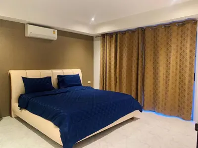 a bedroom with a bed with blue sheets and a window at Rawai Condominium By Wijitra in Phuket Town