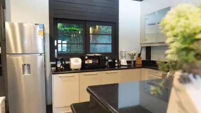 a kitchen with a stainless steel refrigerator and windows at Jaokhun Hilltop Kamala, Phuket in Kamala Beach