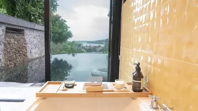a window with a table with a laptop and two glasses at Jaokhun Hilltop Kamala, Phuket in Kamala Beach