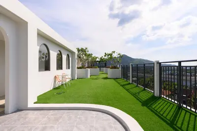 a balcony with green grass on a white building at Fantasea Condo Kamala B204 2BDRM by Phuket Sabay Rent in Kamala Beach