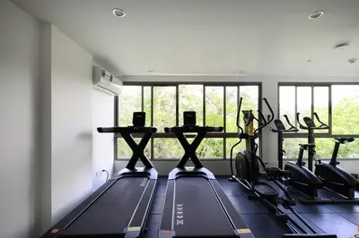a gym with several treadmills and a row of windows at Fantasea Condo Kamala B204 2BDRM by Phuket Sabay Rent in Kamala Beach