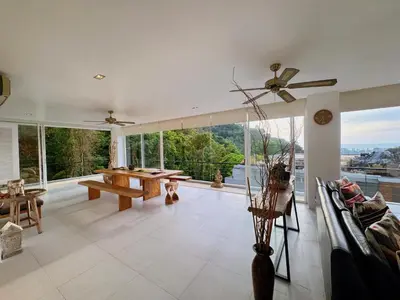 a large living room with tables and a large window at Peaceful The Trees Kamala Hillside in Kamala Beach