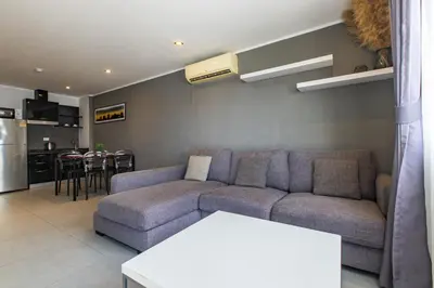 a living room with a couch and a kitchen at Modern Condo - 1BR T1 -501 in Chalong