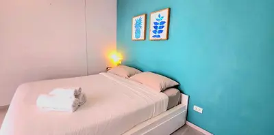 a bedroom with a white bed with a blue wall at Cozy Apartment-1BR T2-524 in Chalong