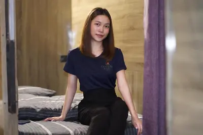 a young woman sitting on a bed at Comfort Hostel Phuket Old Town by MaTong in Phuket Town