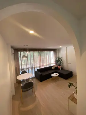 a living room with a black couch and a table at Apartment in Rawai in Ban Saiyuan (1)