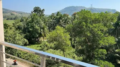 a person riding a motorcycle down a dirt road with trees at New apartment with mountain view in Ban Mai Salae