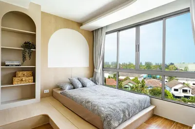 a bedroom with a bed and a large window at Kamala Beach View 1 BdR Roof Pool 500 mbps WiFi in Kamala Beach