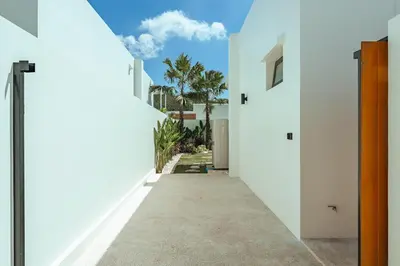 a hallway between two white buildings with a blue sky at Staylar Pool Villas - Bangtao in Ban Pak Lak