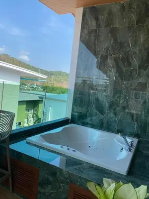 a bath tub in a room with a large window at Mountain breeze villa phuket in Ban Bang Khu