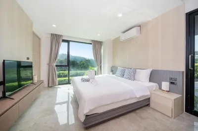 a bedroom with a large bed and a flat screen tv at Luxury Pool Access 2BR Patong in Patong Beach