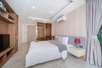a bedroom with a white bed and a television at Luxury Pool Access 2BR Patong in Patong Beach