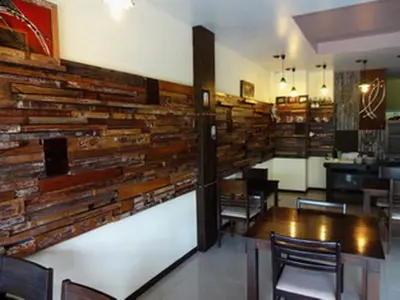 a dining room with a wall made out of logs at Athome Hotel Nanai 8 in Patong Beach