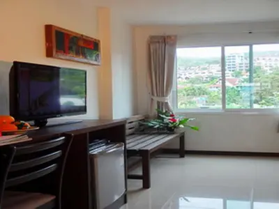 a living room with a desk with a television and a window at Athome Hotel Nanai 8 in Patong Beach