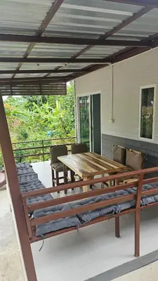 a patio with a wooden table and chairs on a deck at Cozy 1-Bedroom Bungalow with Shared Pool in Rawai in Nai Harn Beach