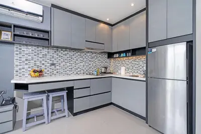 a kitchen with gray cabinets and a stainless steel refrigerator at Enjoy Tropical Bliss in Kamala Suite CTG L704, Top Facilities, near FantaSea & Café Del Mar Beach Club in Kamala Beach
