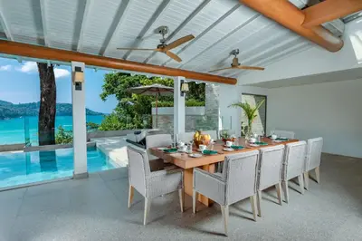 a dining room with a table and chairs and a pool at Villa Amankara in Phuket Town