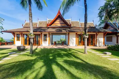 a house with palm trees in front of it at Villa Talaefun - Luxury Oceanfront Fully Serviced in Kamala Beach