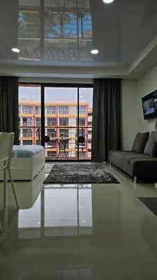 a living room with a couch and a large window at Cosy studio near the best beach on Phuket in Ban Mai Salae