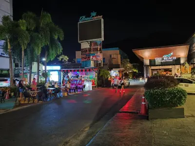 a city street at night with people sitting at tables at 7 Floor - Pool view Studio room at TBHR near Kata beach in Kata Beach