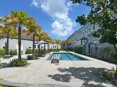 a swimming pool with palm trees next to a building at The Rich Villas Palai in Chalong