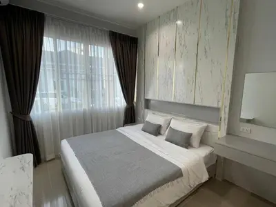 a bedroom with a large bed and a window at The Rich Villas Palai in Chalong