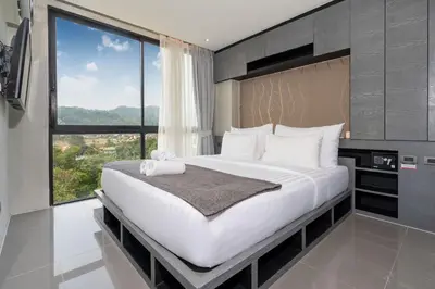 a bedroom with a large bed with a large window at Tropics Kamala Hill View Studio CTG P613 near Beach and Fantasea in Kamala Beach