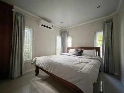 a bedroom with a bed with white sheets and windows at Home Tambon Bang tao 2BR Near Beach in Surin Beach