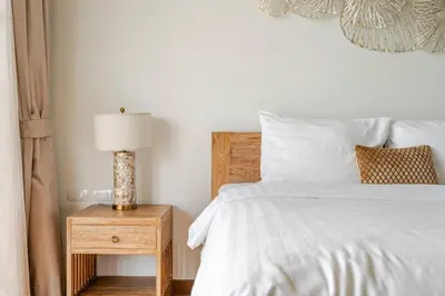 a bedroom with a white bed and a table with a lamp at WEG Laguna Residence in Thalang