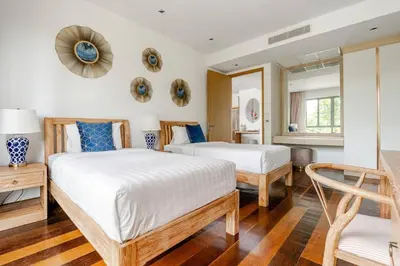 a bedroom with two beds and a chair at WEG Laguna Residence in Thalang
