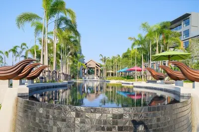 a pool at a resort with umbrellas and palm trees at Surin Mida Grande residence with jacuzzi and sea view - Bang Tao & Surin beach in Surin Beach
