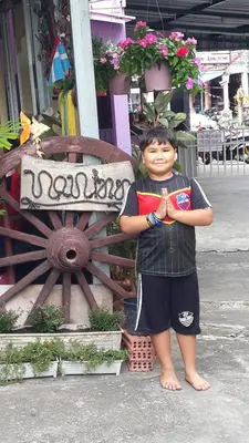 a young boy standing next to a wooden wheel at Nan Inn Bungalow in Karon Beach