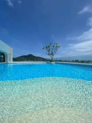a blue swimming pool with a tree in the middle at Fantasea Kamala Walk to Beach Pool & Gym Modern 1BR in Kamala Beach