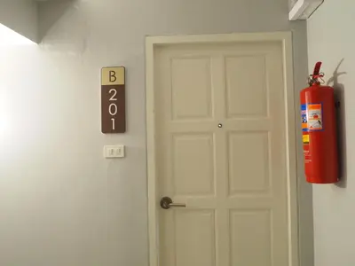 a fire extinguisher sign next to a door with a fire hydrant at The Village Poshtel in Ban Khlong Haeng