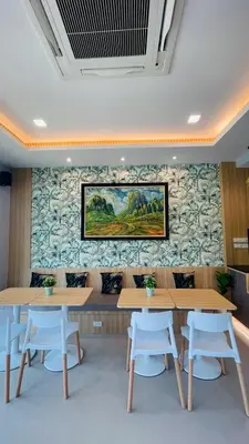 a room with tables and chairs and a painting on the wall at The Village Poshtel in Ban Khlong Haeng